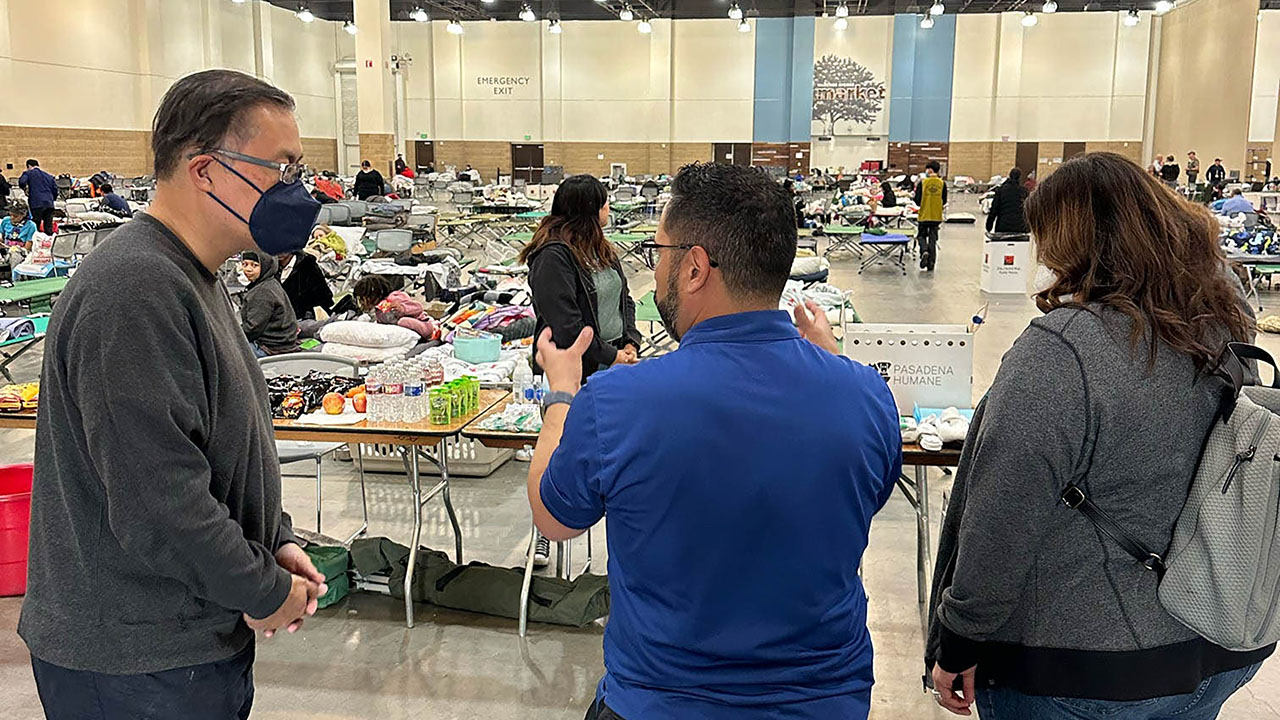 Fernando Fierro, vice president of nursing services at AltaMed (in blue), discusses evacuation shelter procedures with first responders.