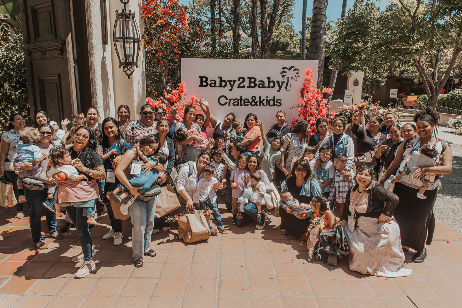 A group of 40 mothers standing in front of a sign that says "Baby2Baby"