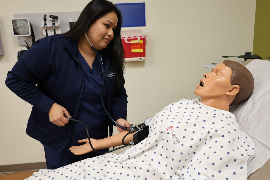 Edith taking a manikin's blood pressure reading